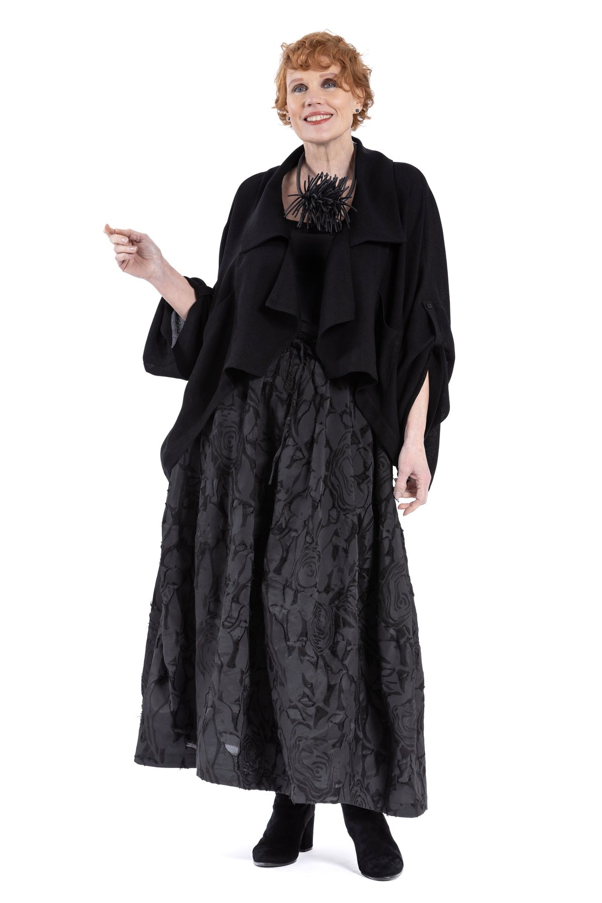 Cropped black lapel jacket with drape collar and patch pockets.