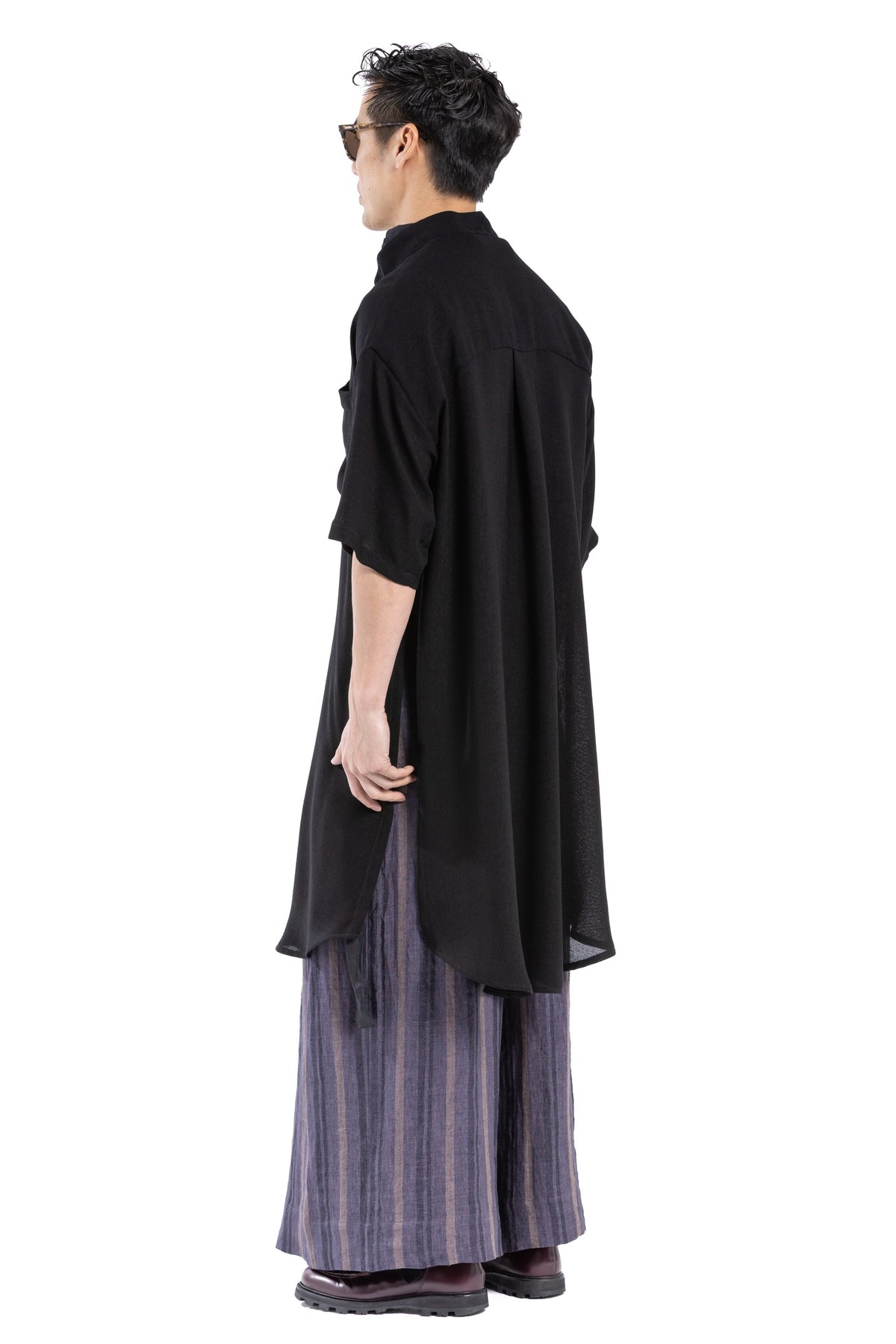 Model wearing black shirt dress styled with sandals.